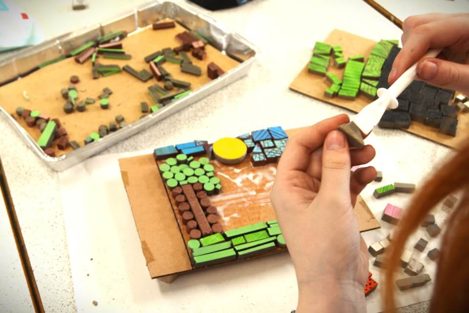 Hands holding and placing brightly coloured mosaic squares